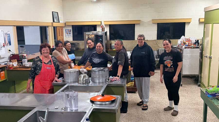 Group of community members standing in a kitchen preparing for people to arrive